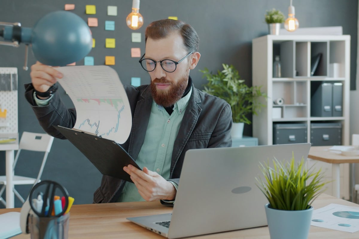 Reviewer examining printed charts beside a computer